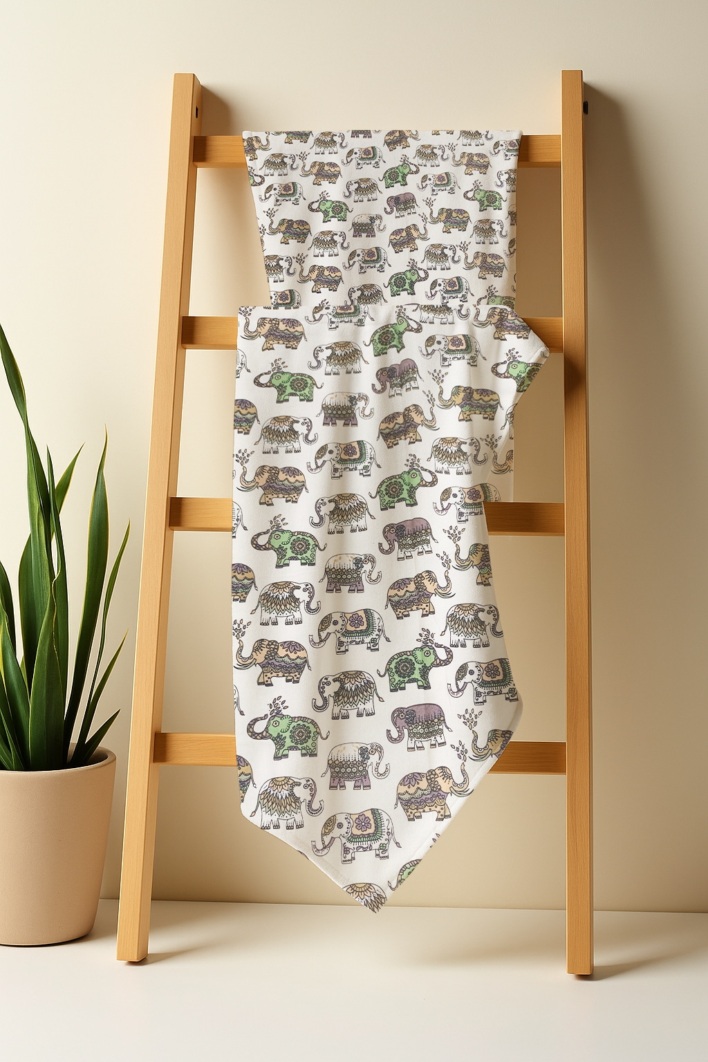 Blanket with elephant pattern draped over a wooden ladder against a beige wall.